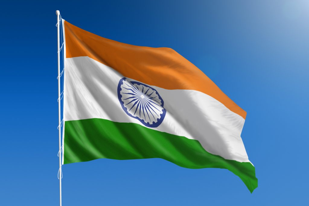 The National flag of India blowing in the wind in front of a clear blue sky